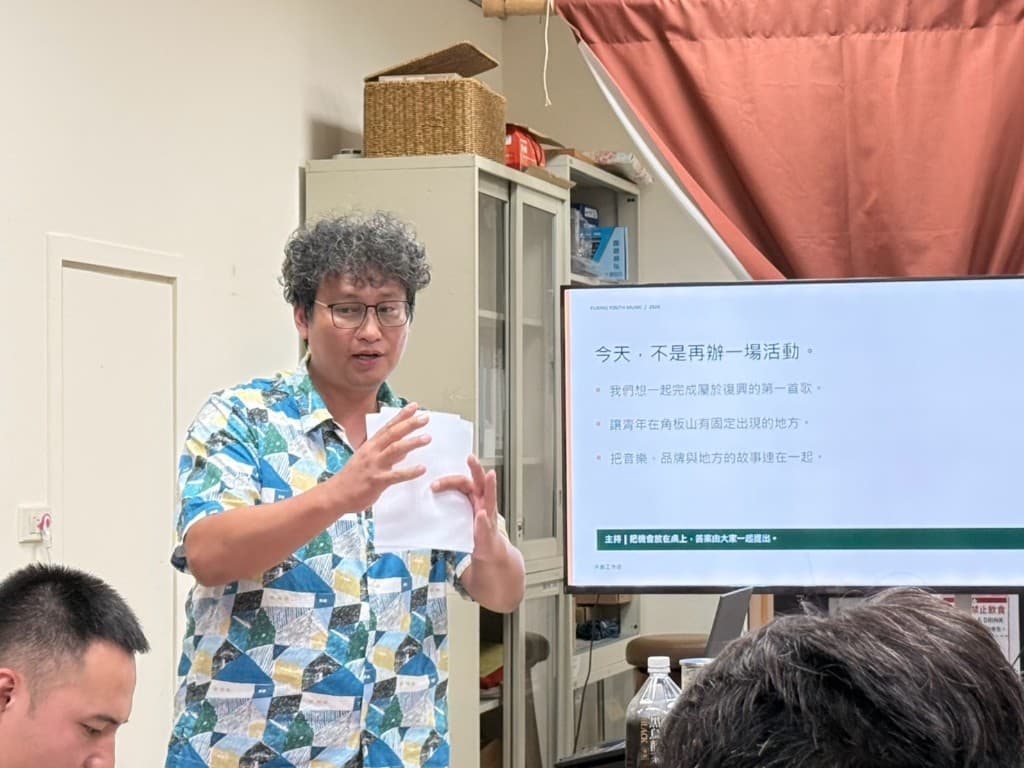 復興音樂人站在投影簡報旁說明,螢幕寫著「今天,不是再辦一場活動」