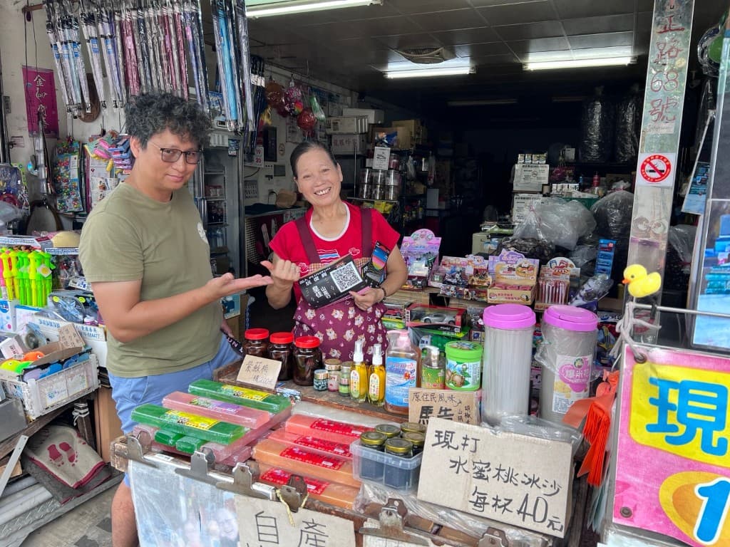 飛鼠先生與在地店家於店內合影,店家手持 PLUWFUN QR 卡