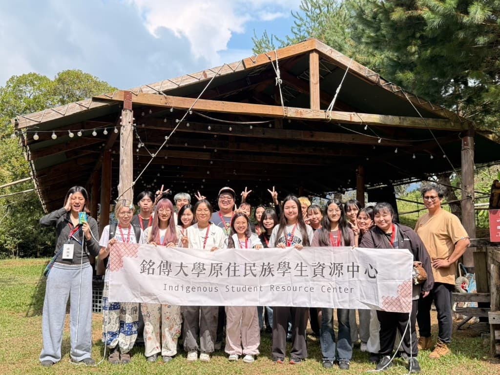 銘傳大學原住民族學生資源中心師生在木棚下拉著中心布條合影