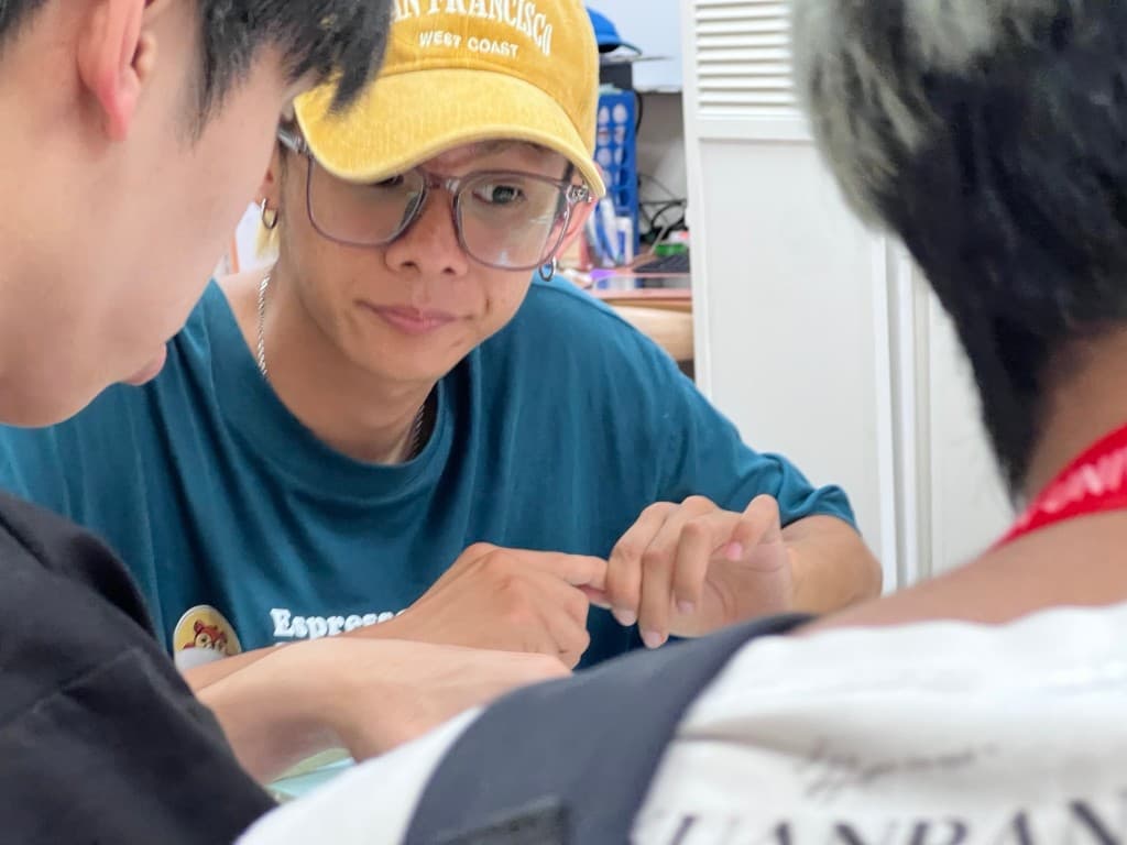 戴黃帽的陪伴者近距離引導學生進行手上的文化體驗