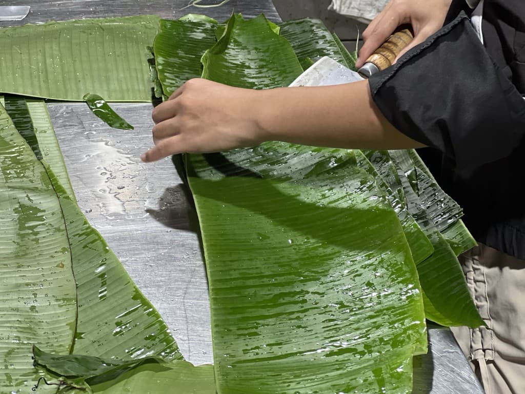 在金屬台上以菜刀整理洗淨的香蕉葉