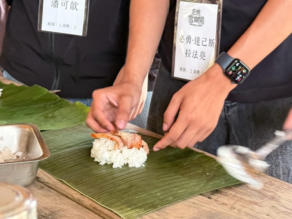 參與者把烤肉放上鋪在香蕉葉上的白飯