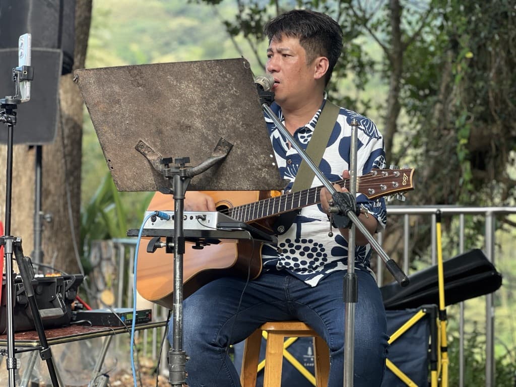 張一凡在角板山戶外場域彈吉他演唱,進行自主音樂實踐